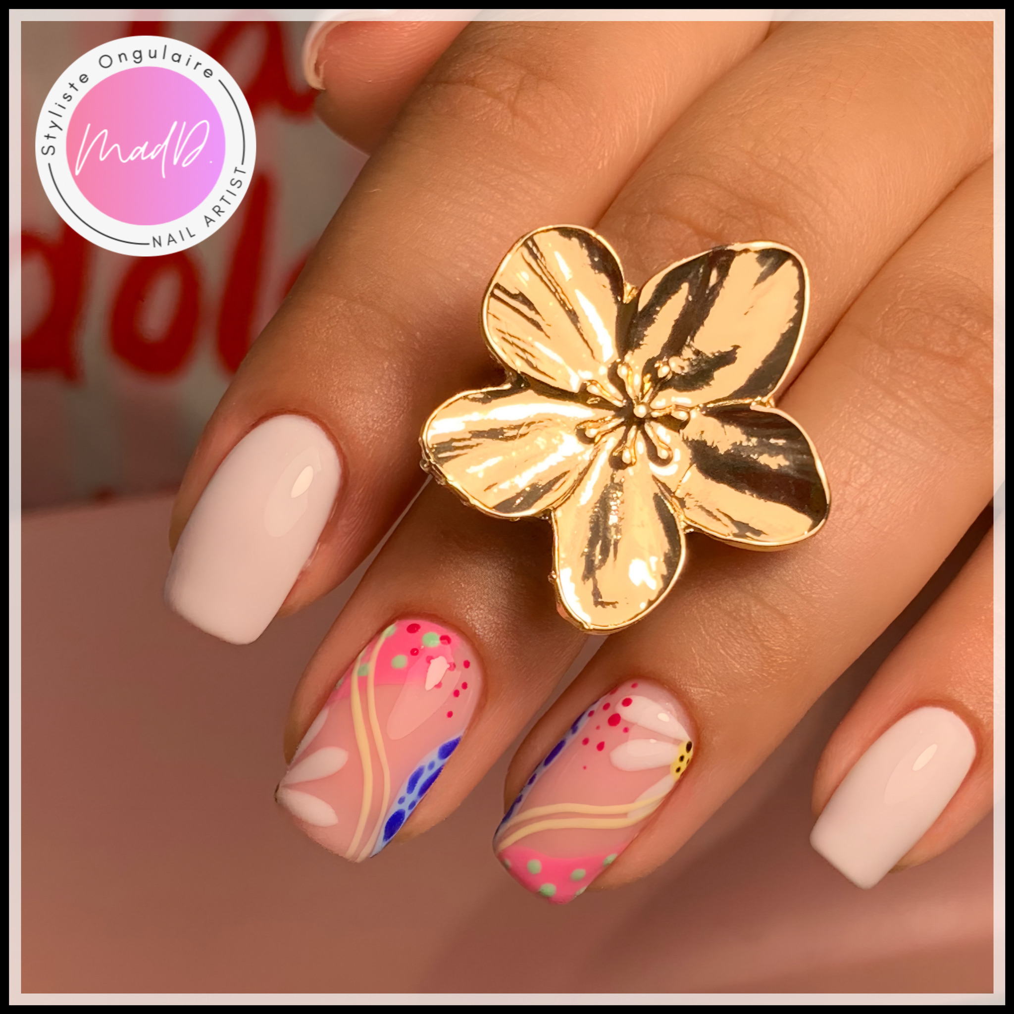 Nail art artistique multicolore aux motifs abstraits roses, bleus et beiges sur ongles carrés nude et blancs.